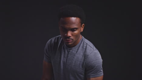 studio portrait of male athlete sport training or exercising in gym folding arms against black background 1