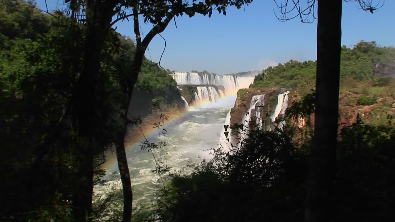 una toma amplia de las cataratas del iguazú con un arco iris en primer plano