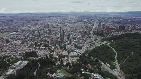 Aerial view of Bogota, Colombia, highlighting the dense urban landscape with modern buildings, residential areas, and the green slopes of Monserrate, framed by the Andres mountain ridge