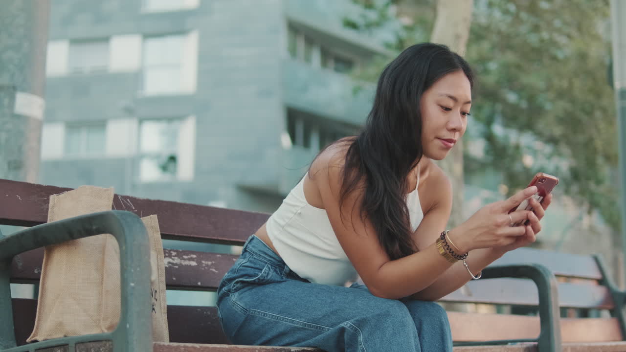 Woman sitting on a bench in a park using her phone