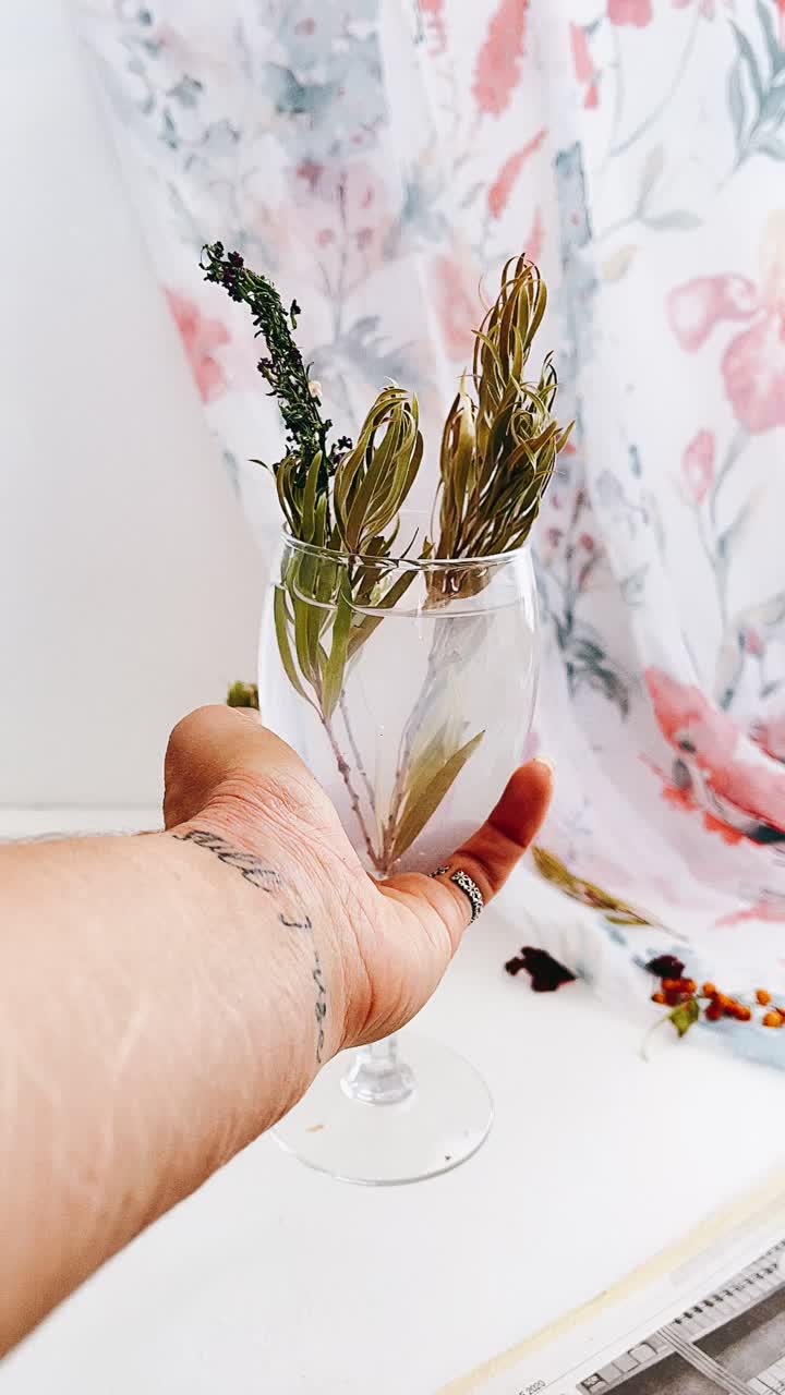 Hand met een glas gedroogde bloemen