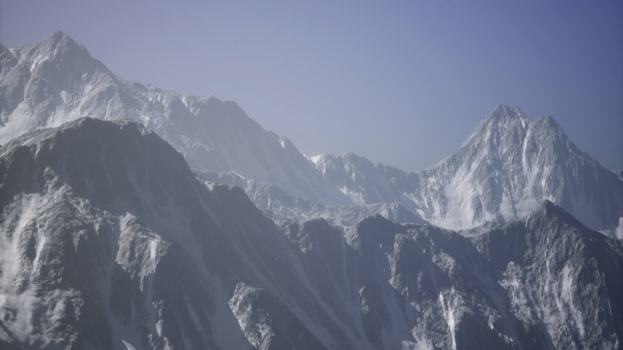 Majestic snow capped mountains rise against a clear sky during daytime