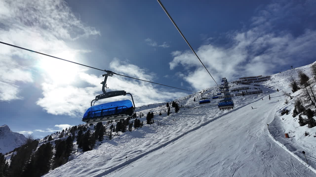 Un suggestivo paesaggio invernale a Sölden, Austria, che mostra una moderna seggiovia che sale una pista da sci alpina innevata sotto un cielo azzurro e limpido. Circondato da imponenti cime montuose