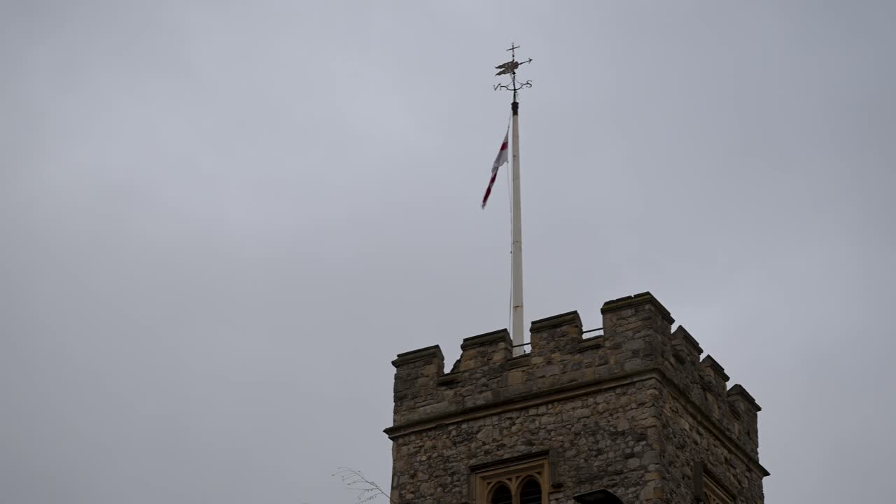 La bandera nacional inglesa ondeando desde la histórica torre de piedra de la Iglesia de Santa María, cerca del Puente de Putney, con vistas al río Támesis en el suroeste de Londres