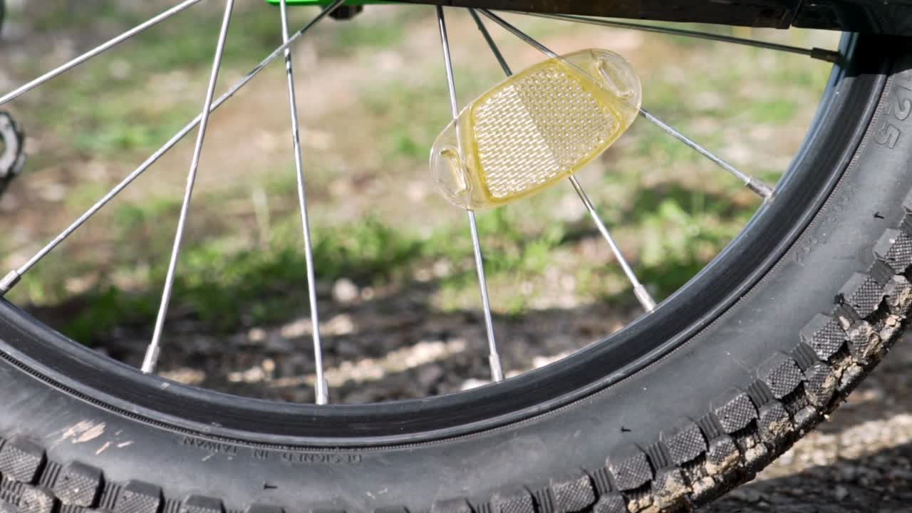 아이의 자전거 바퀴와 프레임 부품, 흐릿한 배경의 녹색 들판, 느린 팬 샷