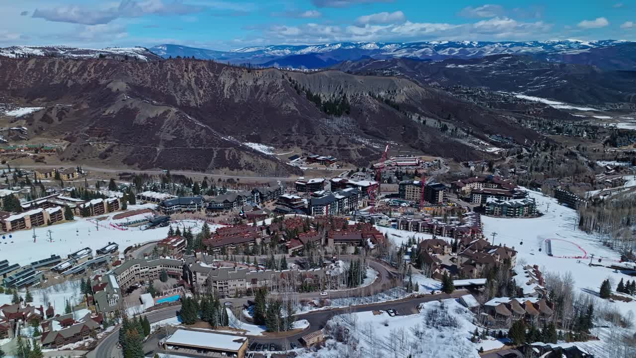 Scenic snow-covered slope cuts through alpine landscape beneath a sunny sky in ski town, Snowmass Colorado USA