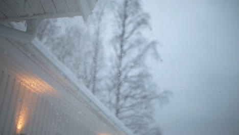 disparo de detalle cercano de una fuerte nevada en una casa escandinava moderna, cámara lenta