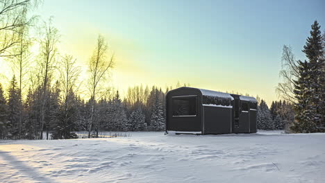 Timelapse-shot-of-a-wooden-cabin-in-a-winter-landscape-with-moving-sun-against-blue-sky-in-the-background-during-evening-time