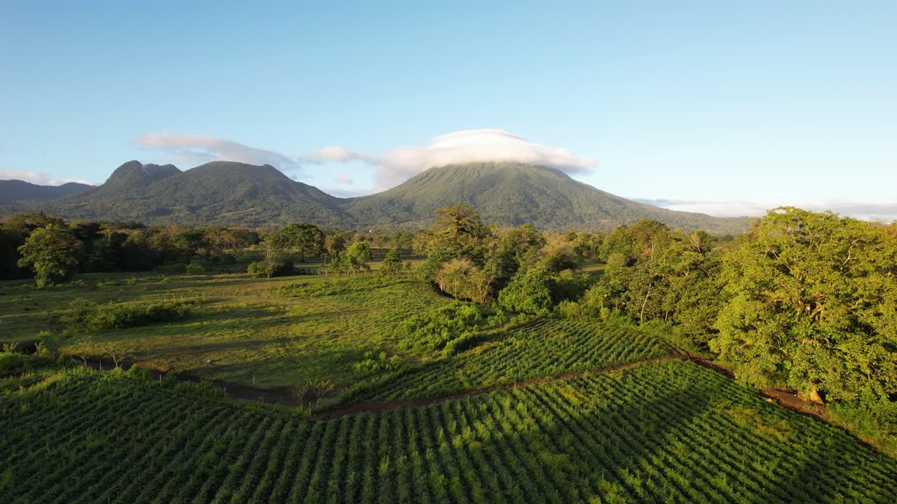 Drone flight above fields an trees towards Arenal Volcano in Costa Rica