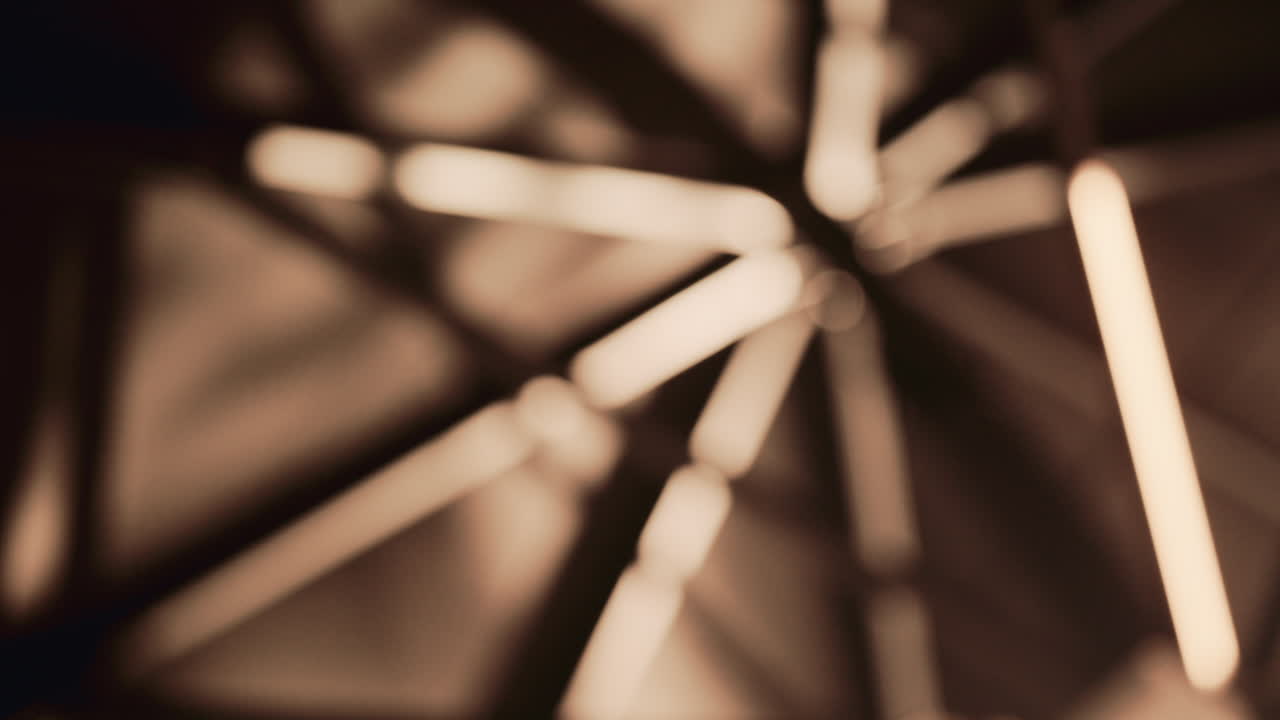 Close up abstract shot of warm linear lights completely out of focus, forming soft glowing shapes on a dark background