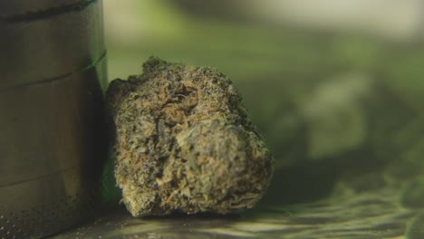 a panning shot to a close up bud of marijuana and a weed grinder