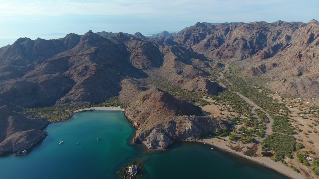 High Strafe Aerial View of Sailboats in a Small Bay with Scenic Mountains and Valley Background