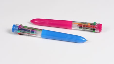 two pens with colored refills on a white. ten different colors. side view. loop motion. rotation 360.