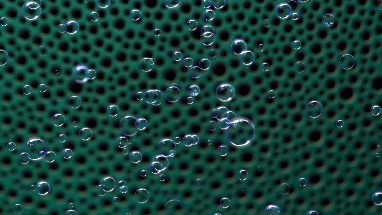 Close Up Green Perforated Surface With Bubbles, Rising Droplets And Glossy Reflections Magnified Abstract