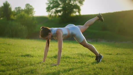 woman athlete involved in fitness in park doing leg lifts on mat. workout. work on a beautiful body in the morning or at sunset. exercises for leg and hip muscles