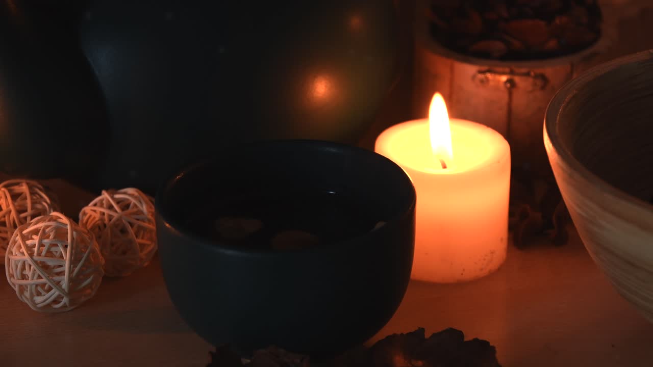 Gambar detail latar belakang yang menenangkan dari sebuah toko teh herbal, dengan lilin berapi berkedip, teko teh, cangkir dengan uap mengepul, rempah-rempah, dan beberapa debu beterbangan.