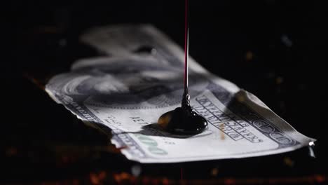 oil being poured onto 100 dollar bill