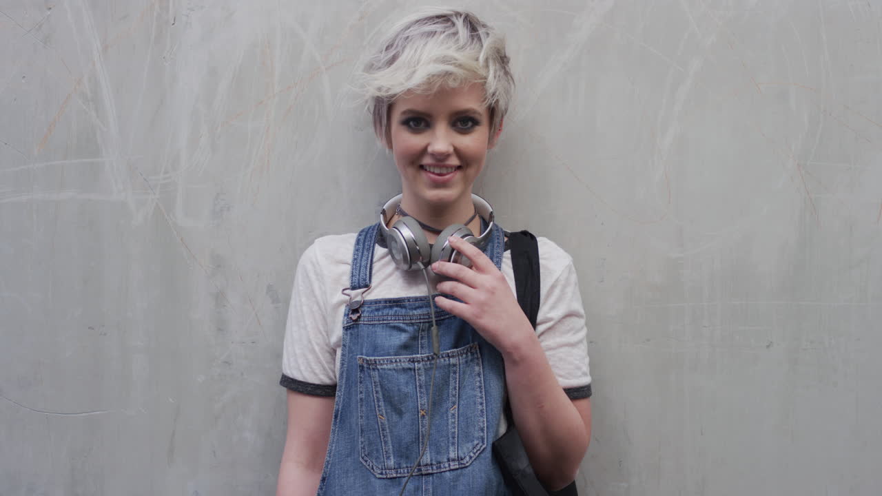 retrato de mujer joven confiada estudiante sonriendo alegre disfrutando de un estilo de vida relajado hermosa chica de moda en fondo de pared de hormigón cámara lenta