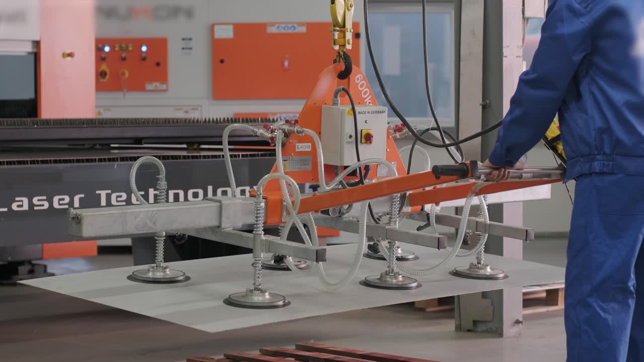 il lavoratore utilizza aspiratori per il trasporto di grandi lastre di metallo