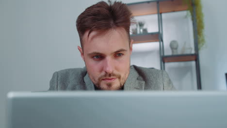 Close-up-businessman-freelancer-at-office-workplace-working-on-laptop-computer-sends-online-messages