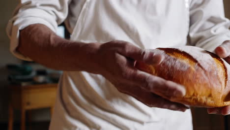 baker holding freshly baked bread loaf