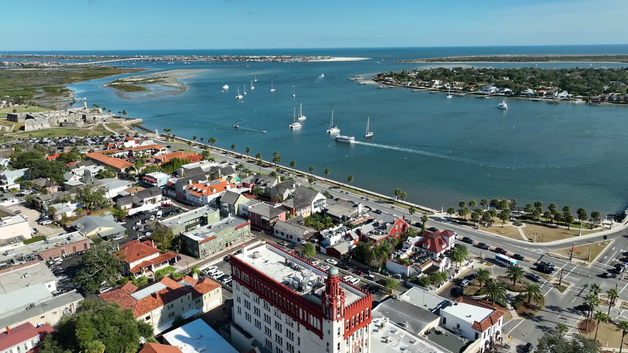 Una vista panoramica aerea di un drone che sorvola Treasury on the Plaza, nel centro storico di St. Augustine, incorniciata da porti turistici sul lungomare e architettura in stile spagnolo