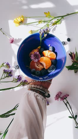 hand holding a bowl of fresh fruit salad with flowers