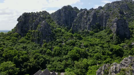 Imágenes-Aéreas-Que-Revelan-Montañas-De-Piedra-Caliza-Y-El-Cielo-Mientras-Desciende-Mostrando-Un-Templo-Budista-Y-El-Bosque