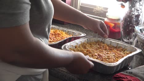 woman preparing two dishes of baked mac and cheese