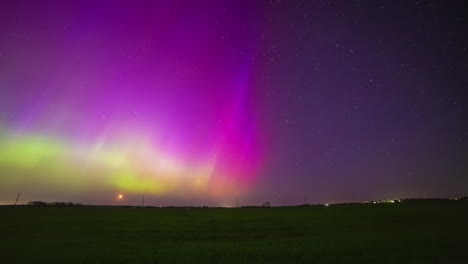 las luces del norte verdes y amarillas bailan en un cielo púrpura durante una luna creciente