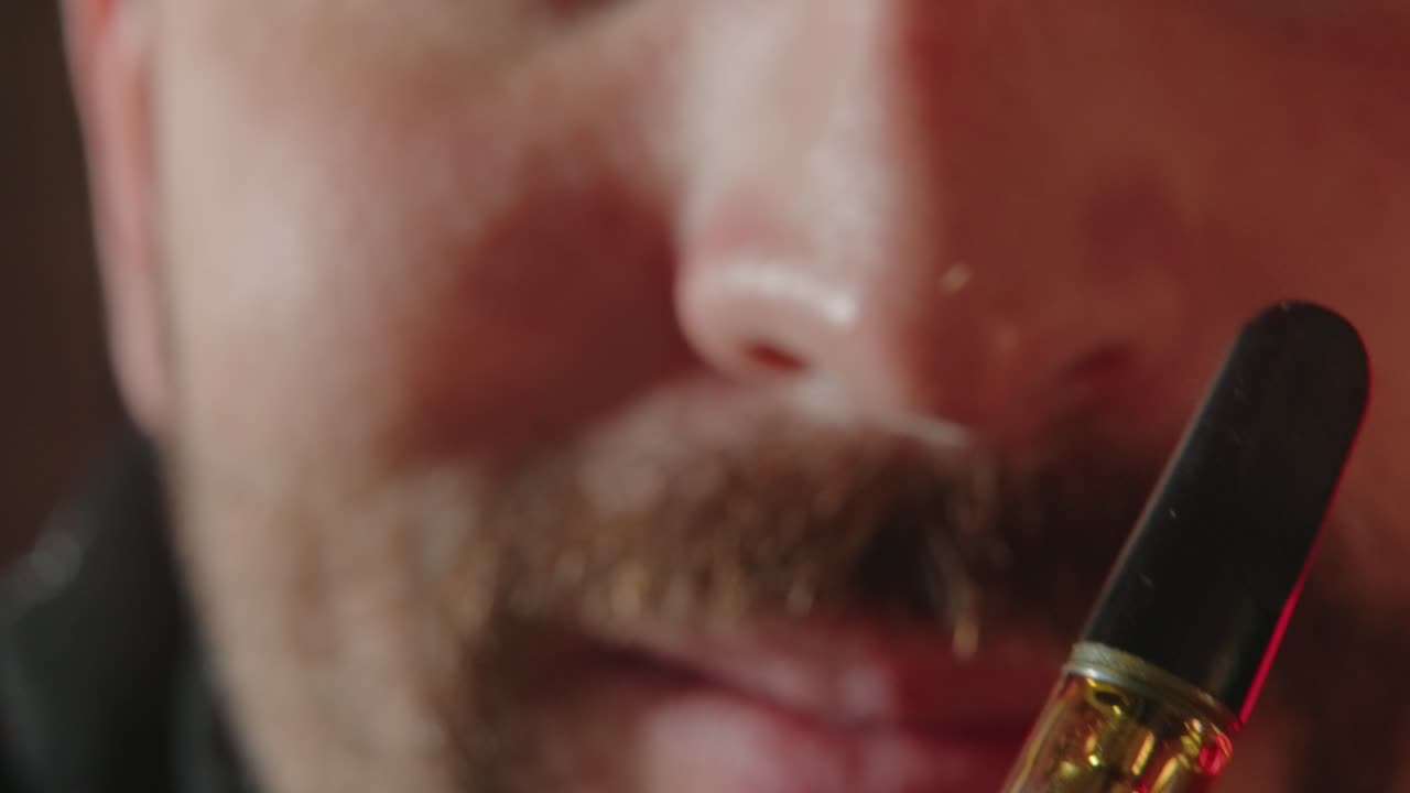 hombre caucásico mirando el vape electrónico con thc - hierba