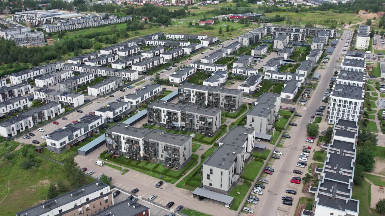 Aerial view of Pilaitė district showing modern residential blocks in the foreground and older grey Soviet-era housing behind, highlighting contrasting architecture and urban development