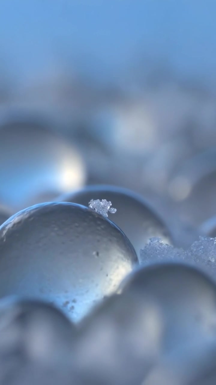 Video verticale: Telecamera con messa a fuoco variabile che rivela perle di vetro in uno studio macro, mostrando cristalli di ghiaccio.