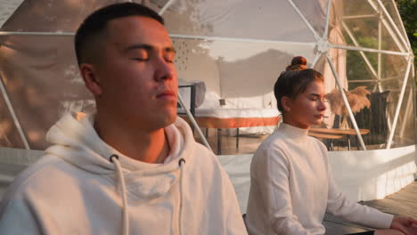 couple meditating in a dome tent at sunset