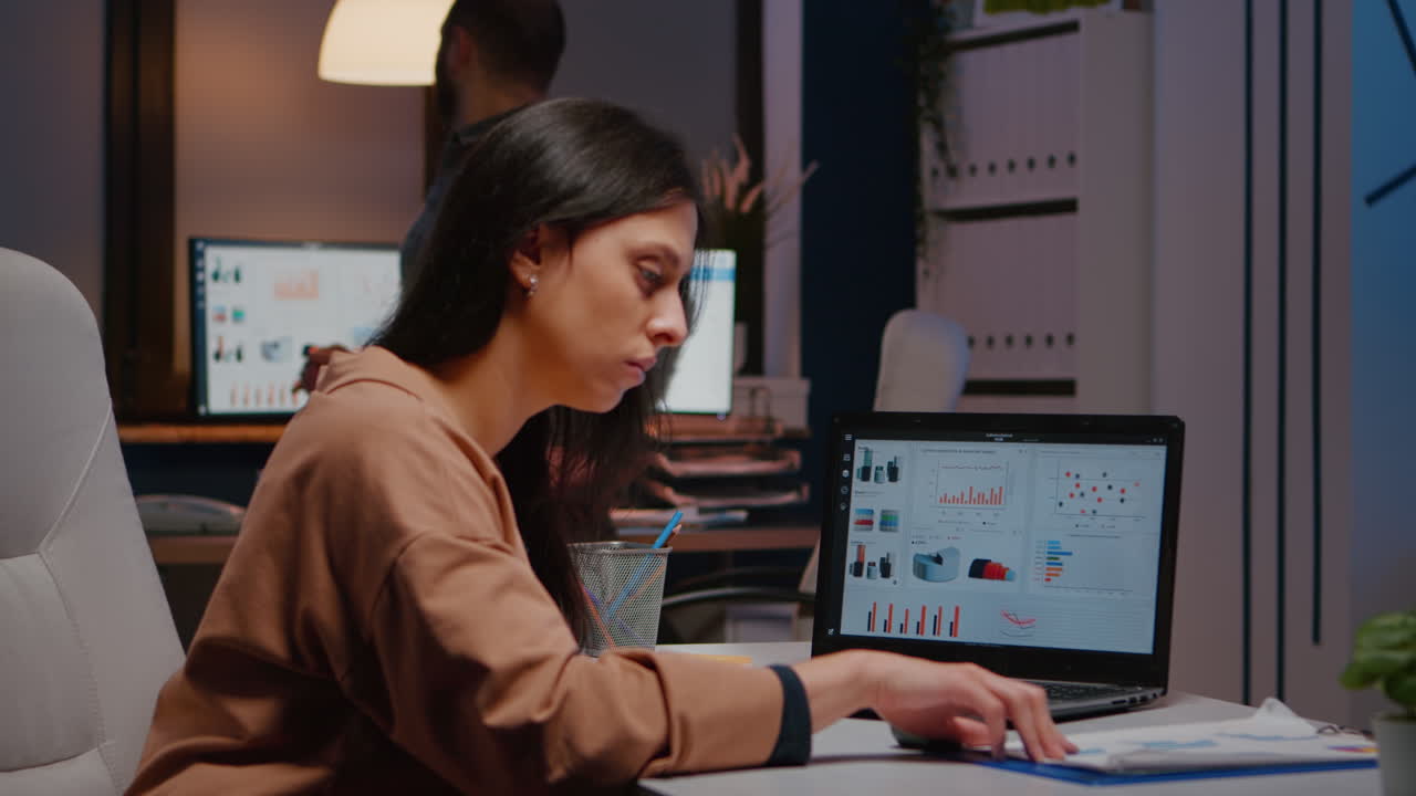 una mujer de negocios ejecutiva cansada y adicta al trabajo escribiendo una estrategia financiera en una computadora portátil.