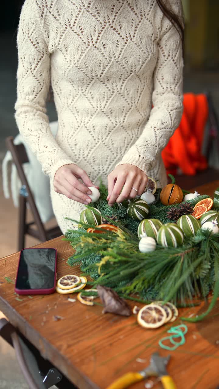 una mujer haciendo una corona de navidad.