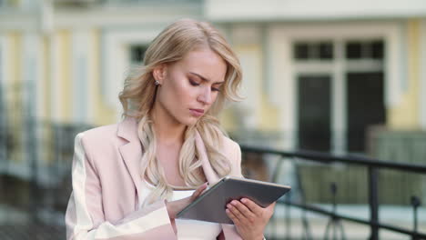 business woman using touchpad for work at street. girl working on tablet outside