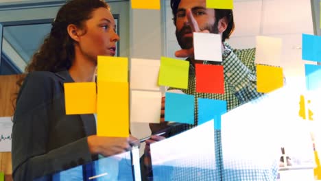 male and female business executives discussing over sticky notes