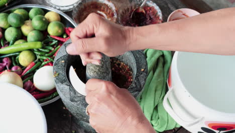 top down view person using stone mortar to making traditional asian spicy sauce