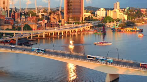 aerial view of city bus and vehicles driving on victoria bridge over brisbane river at sunset in qld, australia