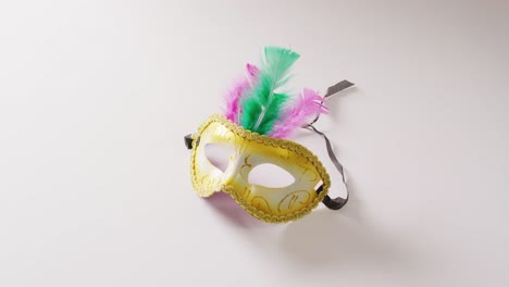 Video-of-masquerade-mask-with-green-and-pink-feathers-on-white-background-with-copy-space