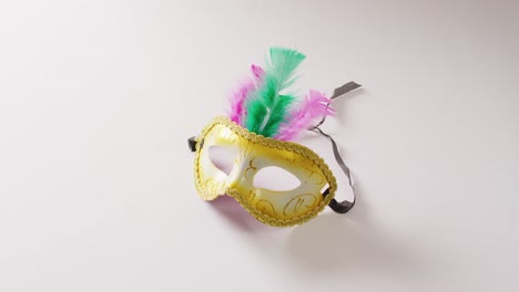 video of masquerade mask with green and pink feathers on white background with copy space