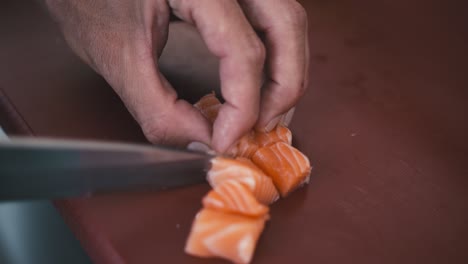 un chef profesional corta un trozo de salmón, preparando un plato de sushi, cocina tradicional japonesa