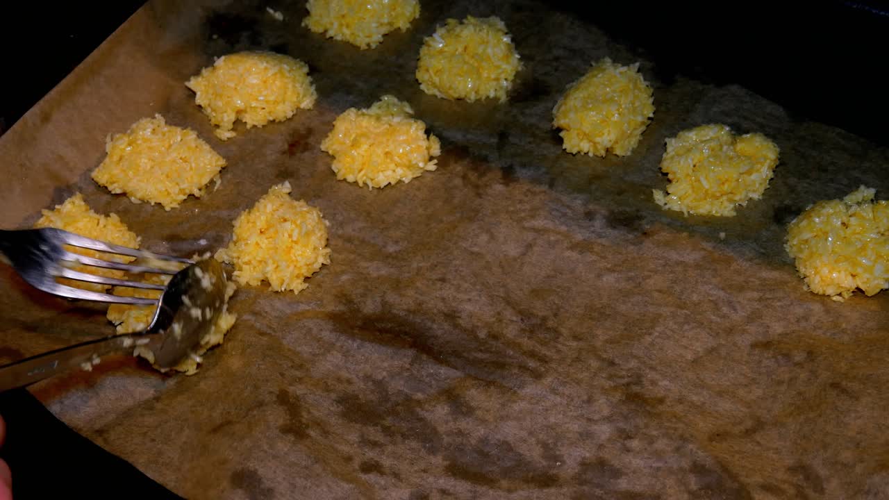 dos hermosas manos femeninas están formando galletas de coco en papel para hornear para cocinar en el horno para obtener deliciosos dulces
