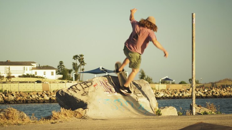 Giovane skater esegue un trick su un blocco di cemento e si allontana, ripresa a mano