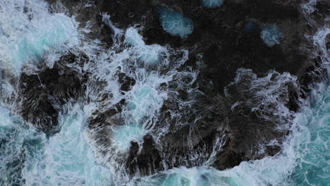 Aerial-zoom-in-as-waves-crash-against-a-rocky-coastline