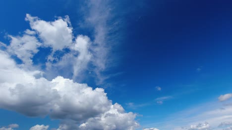 fluffy white cumulus clouds float across bright blue sky, nature scene