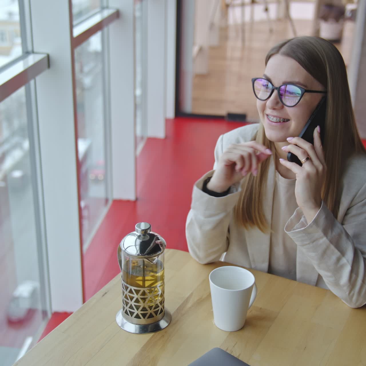 Friendly talk on the phone in a spacious office. Lady in light clothes speaks on the phone being in a good mood. High angle view