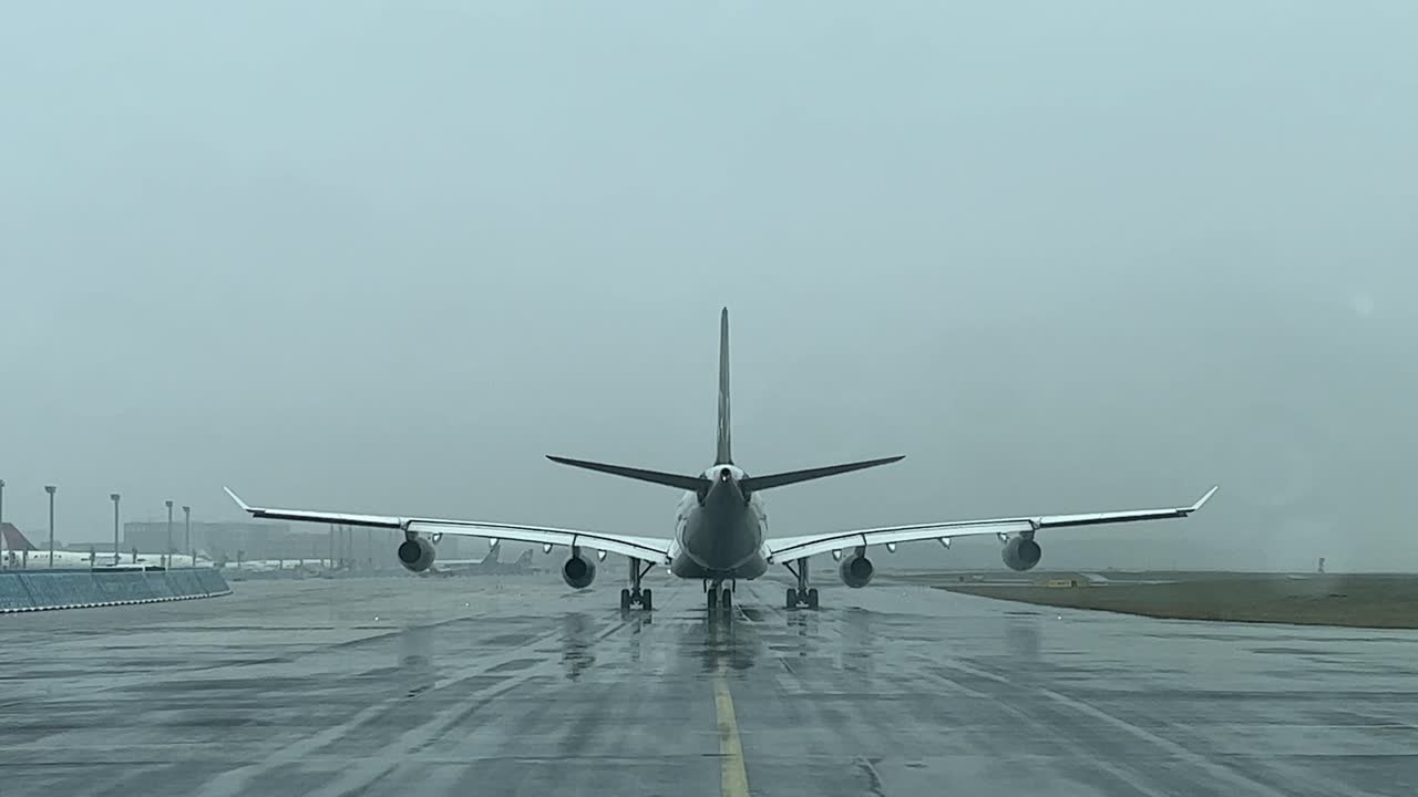 vista trasera de un airbus a340 gravando lentamente en una calle de rodaje durante una lluvia de nieve