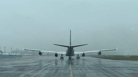 rear view of an airbus a340 taxing slowly on a taxiway during a snow shower